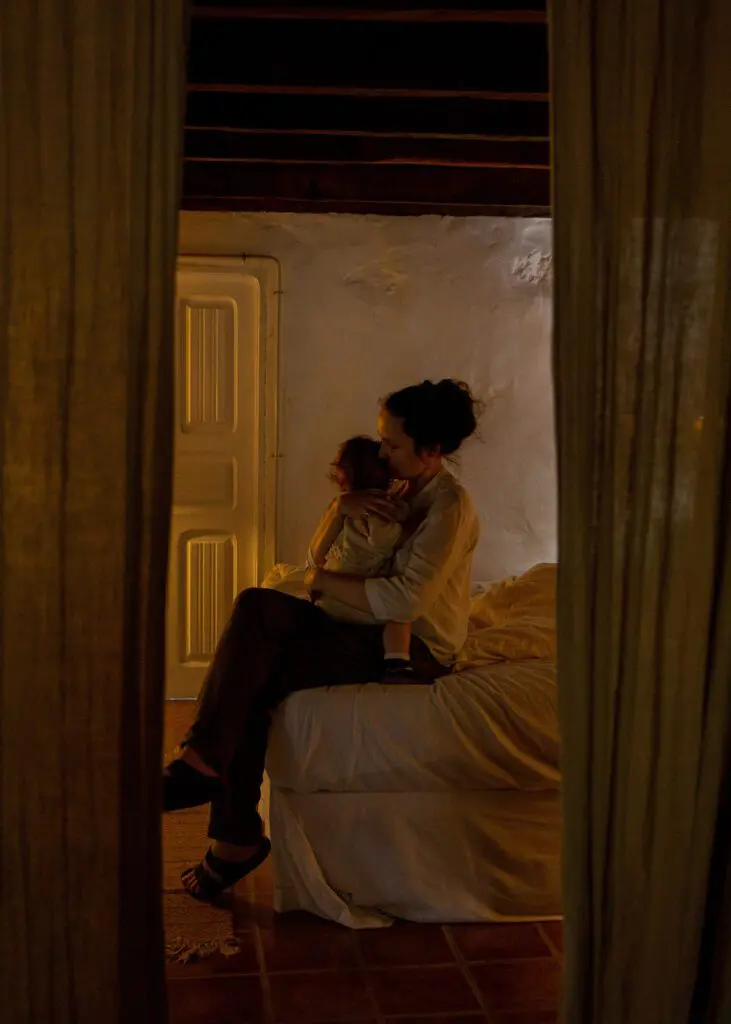 Mom cuddling child while sitting on bed