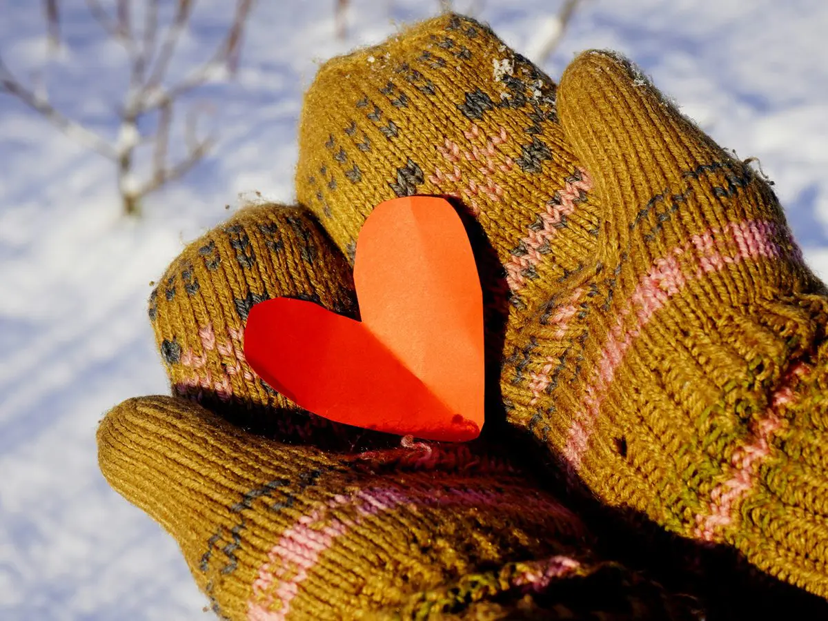Love your sensitive self — holding a paper heart in mittened hands