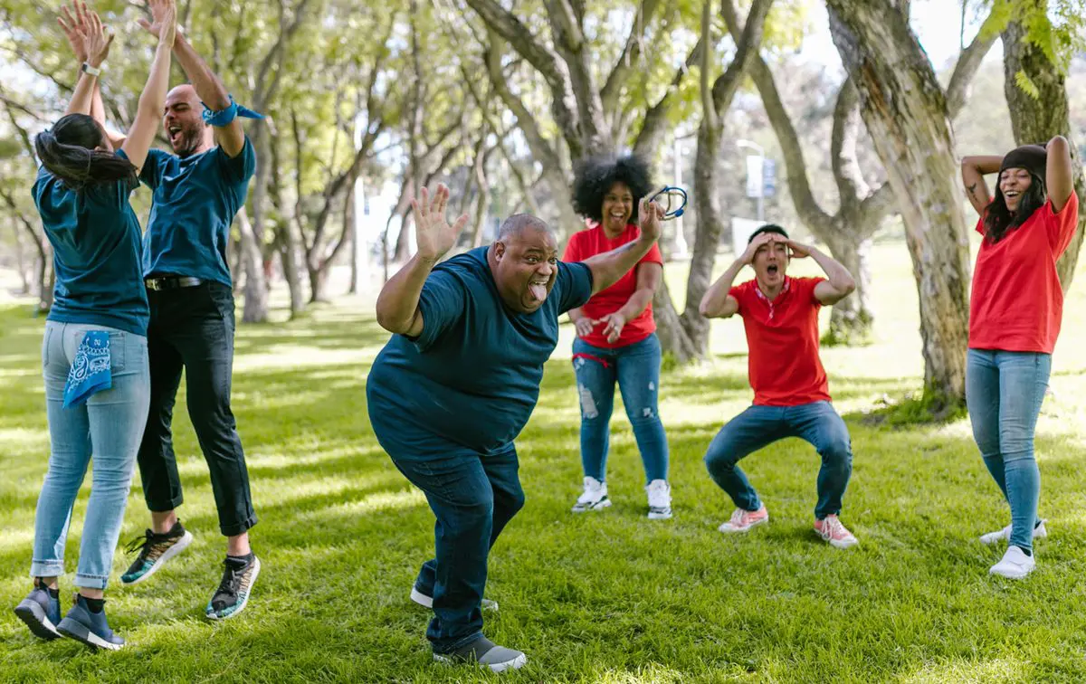 The benefits of play on the body — friends laughing through a game of charades in the park
